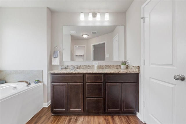 bathroom with vanity, a bath, and hardwood / wood-style flooring