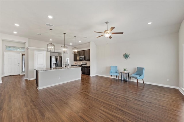 kitchen featuring dark hardwood / wood-style floors, ceiling fan, an island with sink, appliances with stainless steel finishes, and dark brown cabinetry