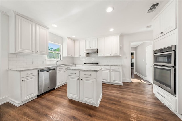 kitchen featuring white cabinets, dark hardwood / wood-style floors, a kitchen island, and appliances with stainless steel finishes