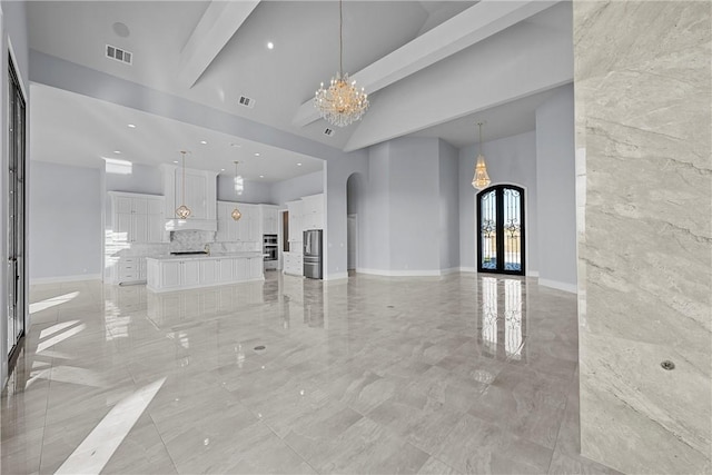 unfurnished living room with beam ceiling, high vaulted ceiling, french doors, and a notable chandelier