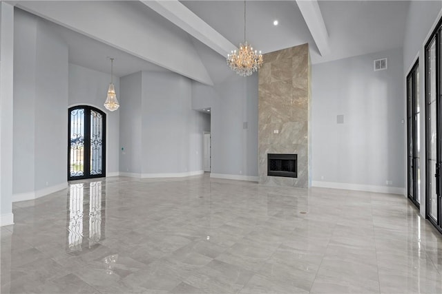 unfurnished living room featuring french doors, a towering ceiling, a fireplace, a notable chandelier, and beamed ceiling