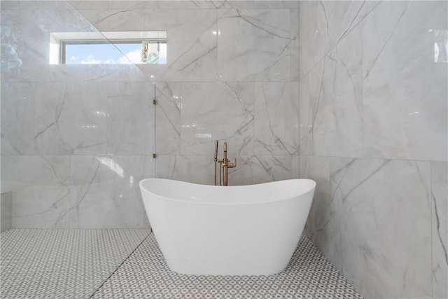 bathroom featuring a washtub and tile walls