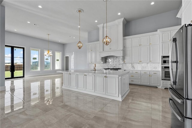 kitchen with white cabinets, hanging light fixtures, an island with sink, tasteful backsplash, and stainless steel appliances