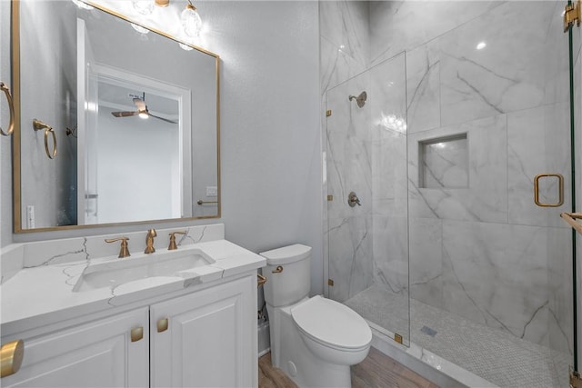 bathroom featuring vanity, ceiling fan, hardwood / wood-style floors, toilet, and a shower with shower door