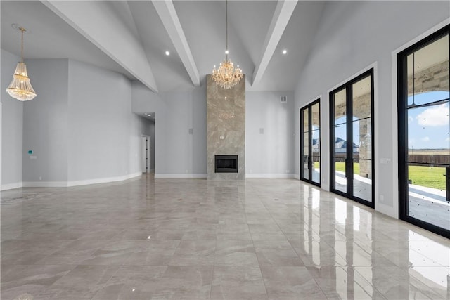 unfurnished living room featuring high vaulted ceiling, french doors, an inviting chandelier, a fireplace, and beamed ceiling