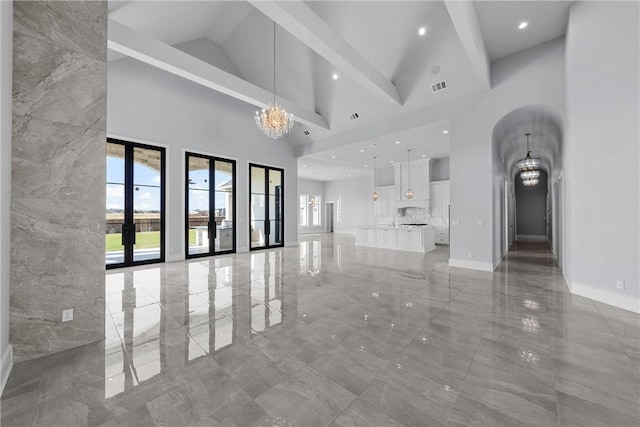 unfurnished living room featuring beamed ceiling, high vaulted ceiling, french doors, and a notable chandelier