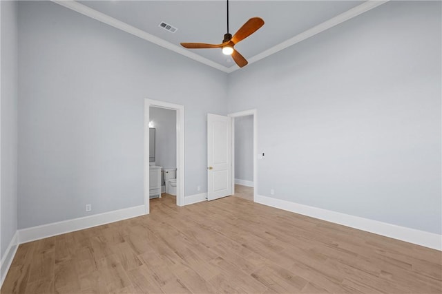 unfurnished bedroom featuring ceiling fan, ensuite bathroom, a towering ceiling, light hardwood / wood-style floors, and ornamental molding