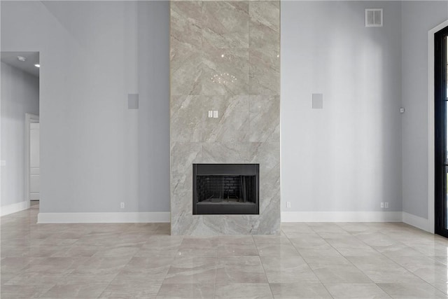 unfurnished living room with a fireplace, a towering ceiling, and tile walls