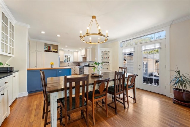 dining room featuring a chandelier, french doors, light wood-style floors, and crown molding