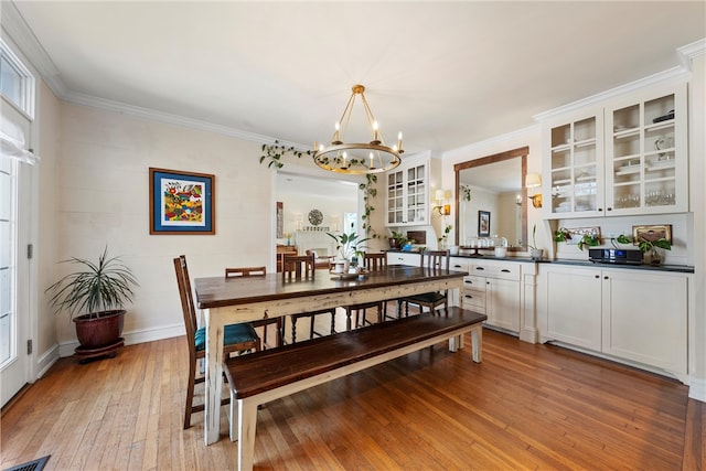 dining room featuring crown molding, visible vents, an inviting chandelier, light wood-style floors, and baseboards