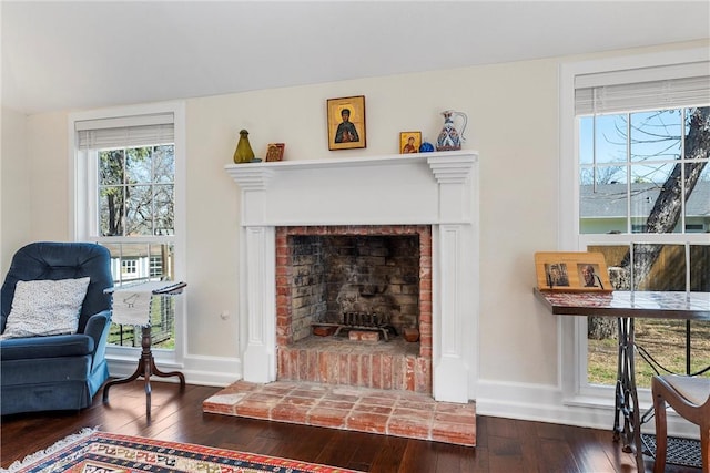 living room featuring dark wood-type flooring, a fireplace, and baseboards