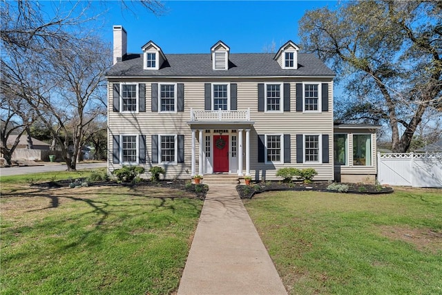 view of front of property featuring a front lawn, a shingled roof, fence, and a gate