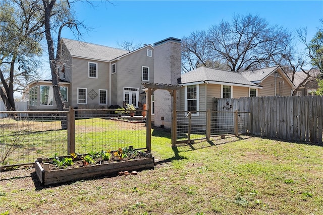 rear view of property with a garden, a yard, a fenced backyard, and a pergola