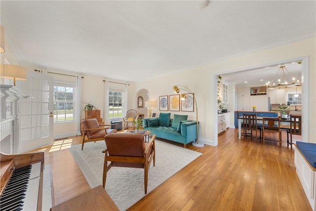 living area featuring light wood finished floors, baseboards, and a notable chandelier