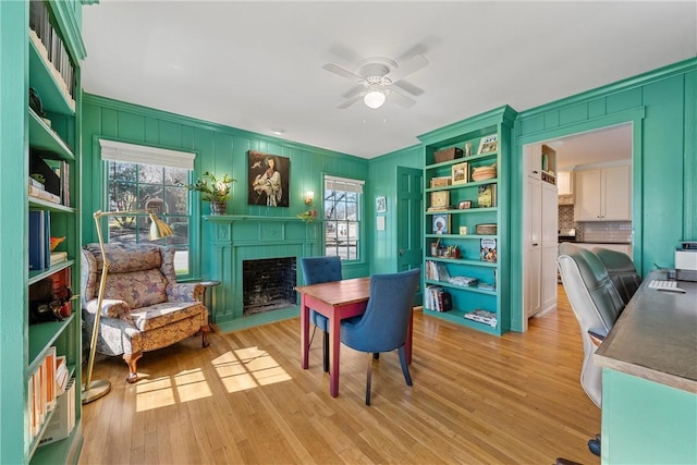 interior space featuring a fireplace with flush hearth, light wood-type flooring, and ceiling fan