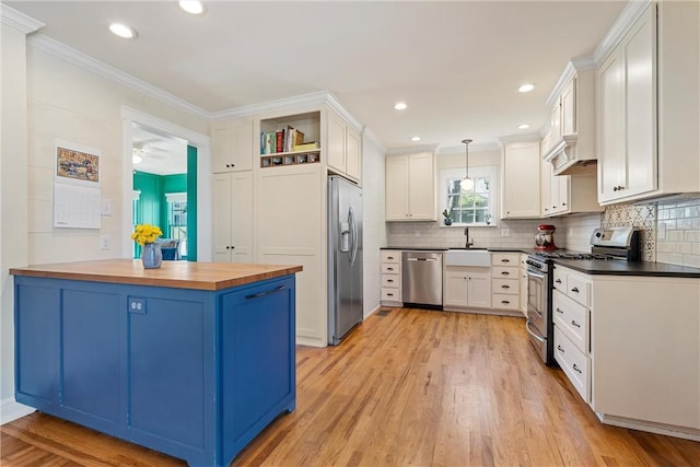 kitchen featuring light wood finished floors, appliances with stainless steel finishes, wooden counters, and crown molding