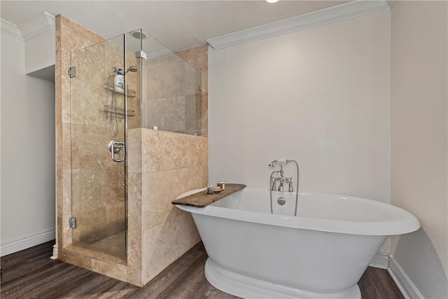 bathroom with ornamental molding, a stall shower, a soaking tub, and wood finished floors