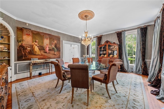 dining area with light hardwood / wood-style floors, crown molding, and a notable chandelier