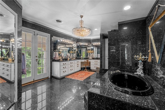 bathroom with a textured ceiling, vanity, a tub to relax in, and french doors