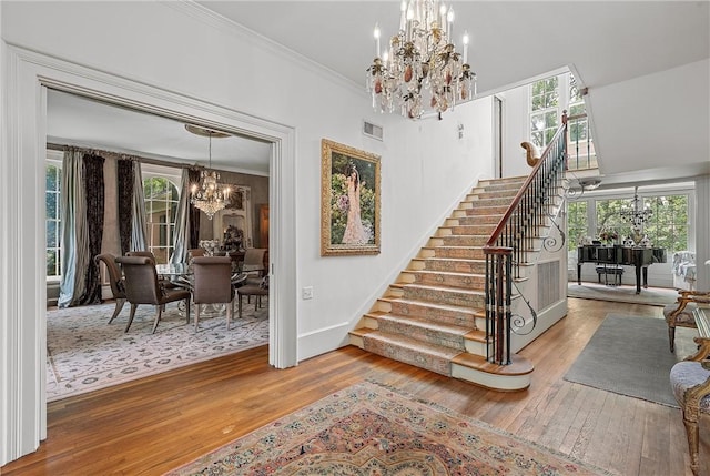 stairway featuring a chandelier, hardwood / wood-style floors, and crown molding