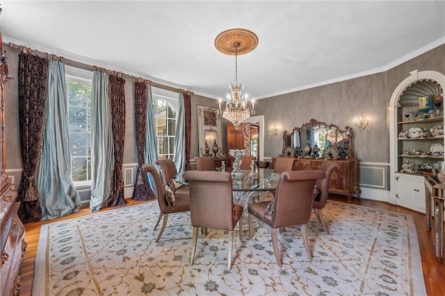 dining room featuring a chandelier, built in shelves, light hardwood / wood-style flooring, and ornamental molding