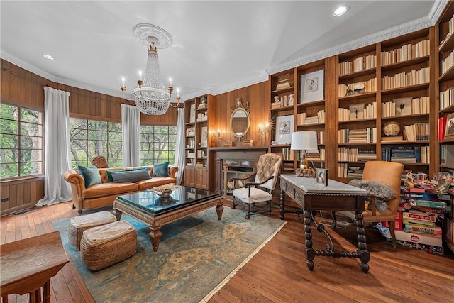 sitting room featuring hardwood / wood-style floors, plenty of natural light, wood walls, and an inviting chandelier