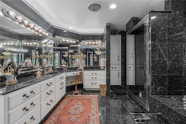 bathroom featuring vanity, a shower with shower door, and a textured ceiling