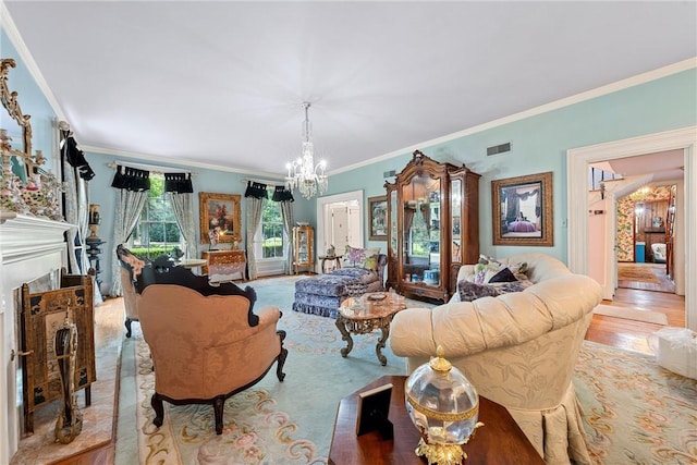 living room with a fireplace, light hardwood / wood-style floors, crown molding, and an inviting chandelier