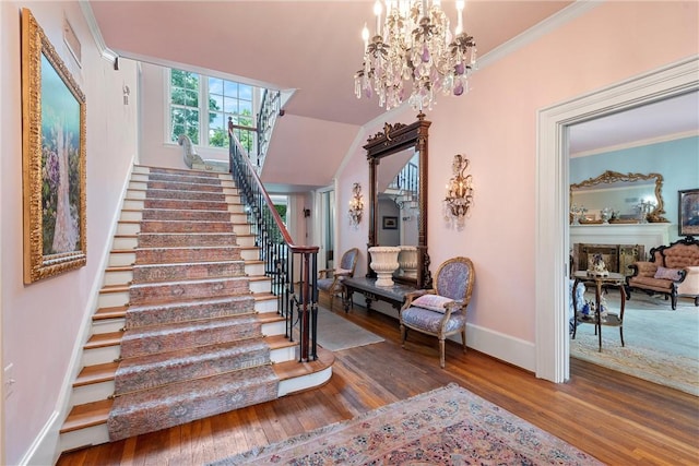 stairs with crown molding, wood-type flooring, and an inviting chandelier