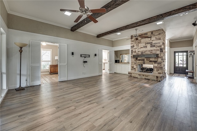 unfurnished living room with beamed ceiling, light hardwood / wood-style floors, and a wealth of natural light