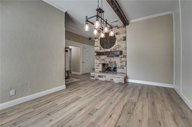 unfurnished living room featuring beam ceiling, a stone fireplace, light hardwood / wood-style flooring, a chandelier, and ornamental molding