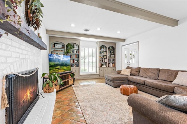 living room featuring beam ceiling, built in features, and a brick fireplace