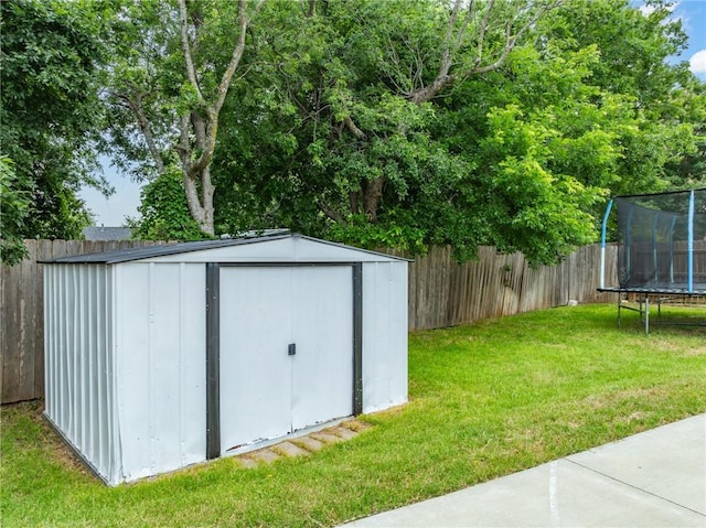 view of outbuilding featuring a trampoline and a lawn