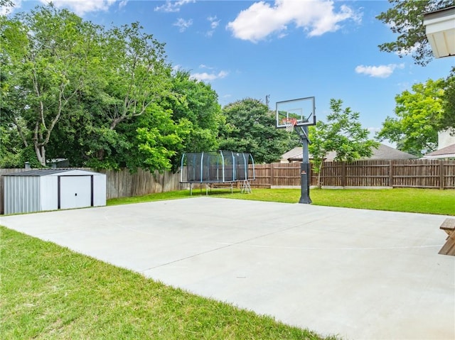 view of sport court with a trampoline and a yard