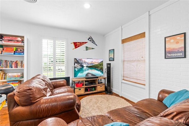 living room with hardwood / wood-style flooring and brick wall