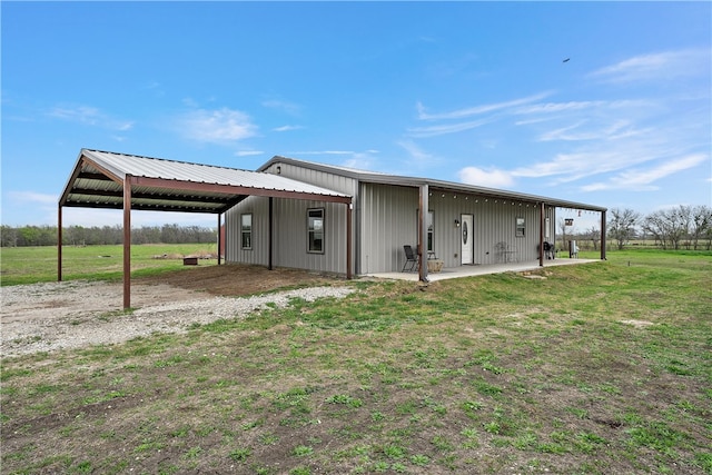 rear view of house featuring a lawn, an outbuilding, and a rural view