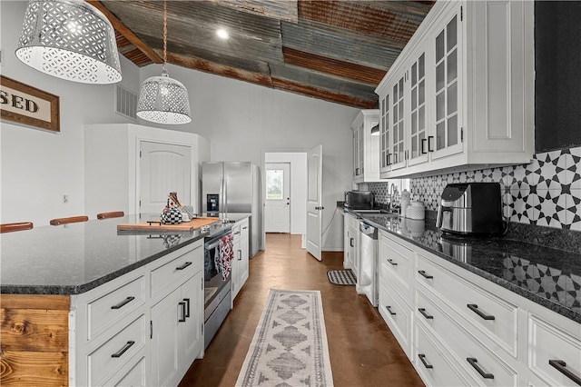 kitchen featuring stainless steel appliances, decorative light fixtures, dark stone countertops, a center island, and white cabinetry