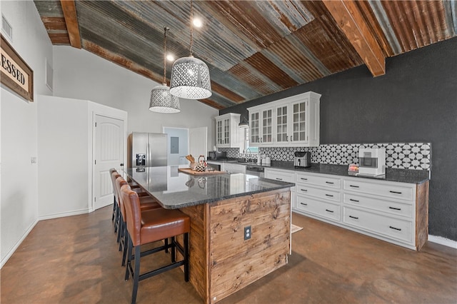 kitchen with backsplash, white cabinets, a kitchen island, a kitchen bar, and stainless steel appliances