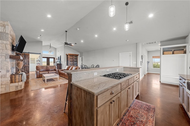 kitchen with light stone counters, stainless steel gas cooktop, a breakfast bar area, hanging light fixtures, and lofted ceiling