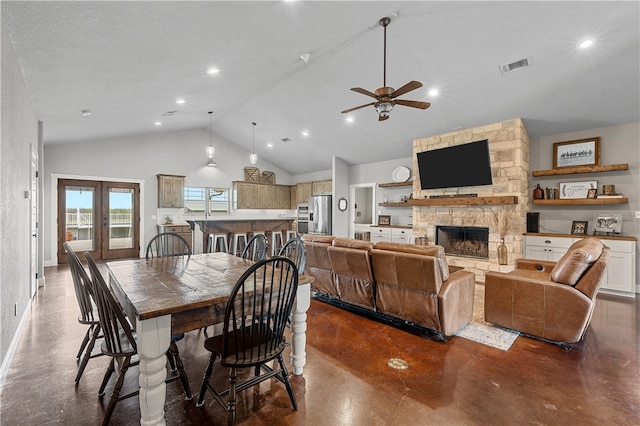 dining room with a stone fireplace, ceiling fan, high vaulted ceiling, and a textured ceiling