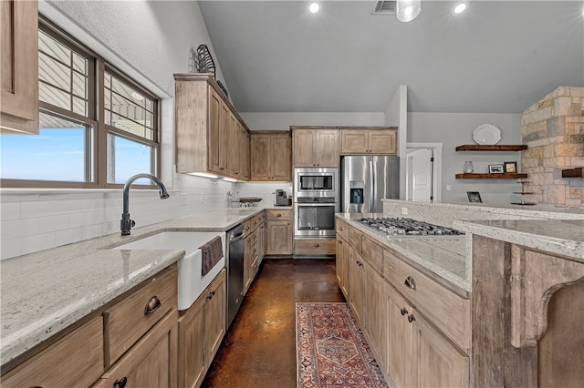 kitchen featuring tasteful backsplash, light stone counters, sink, and stainless steel appliances