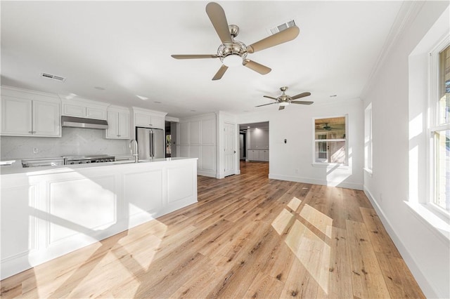 kitchen featuring white cabinetry, backsplash, stainless steel fridge, and light hardwood / wood-style flooring