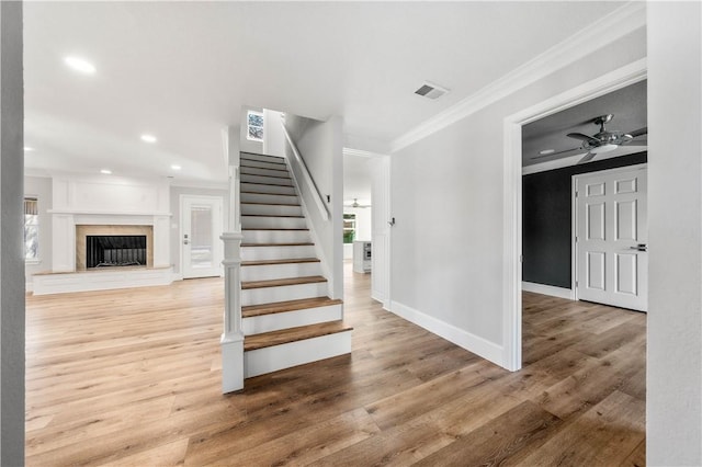 staircase with hardwood / wood-style flooring, ornamental molding, and ceiling fan