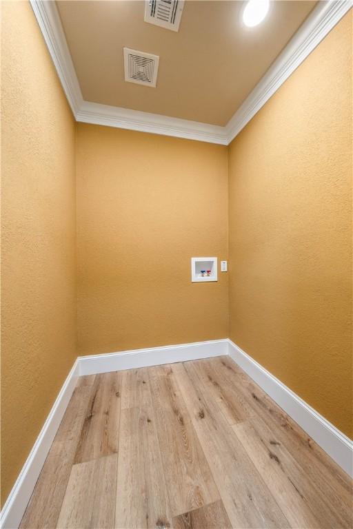 laundry area with washer hookup, crown molding, and wood-type flooring