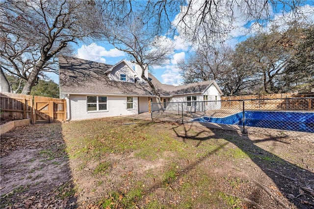 back of property with a fenced in pool and a yard