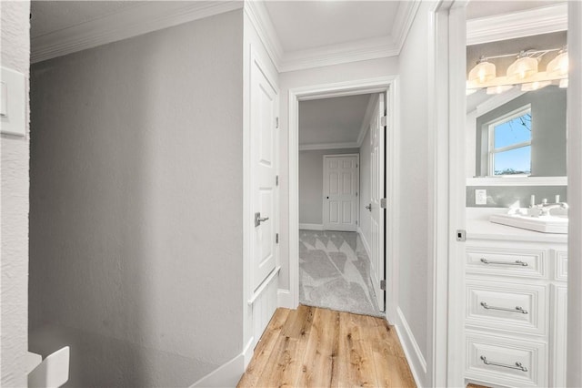 corridor featuring sink, crown molding, and light hardwood / wood-style flooring