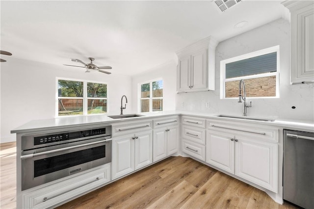 kitchen featuring sink, kitchen peninsula, white cabinets, and appliances with stainless steel finishes