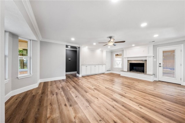 unfurnished living room featuring crown molding, ceiling fan, a fireplace, and light hardwood / wood-style floors