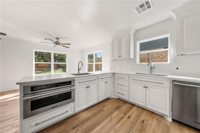 kitchen featuring appliances with stainless steel finishes, kitchen peninsula, sink, and white cabinets