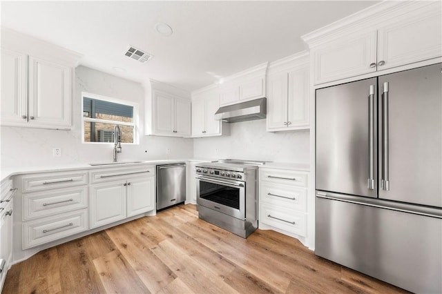 kitchen with high end appliances, sink, and white cabinets